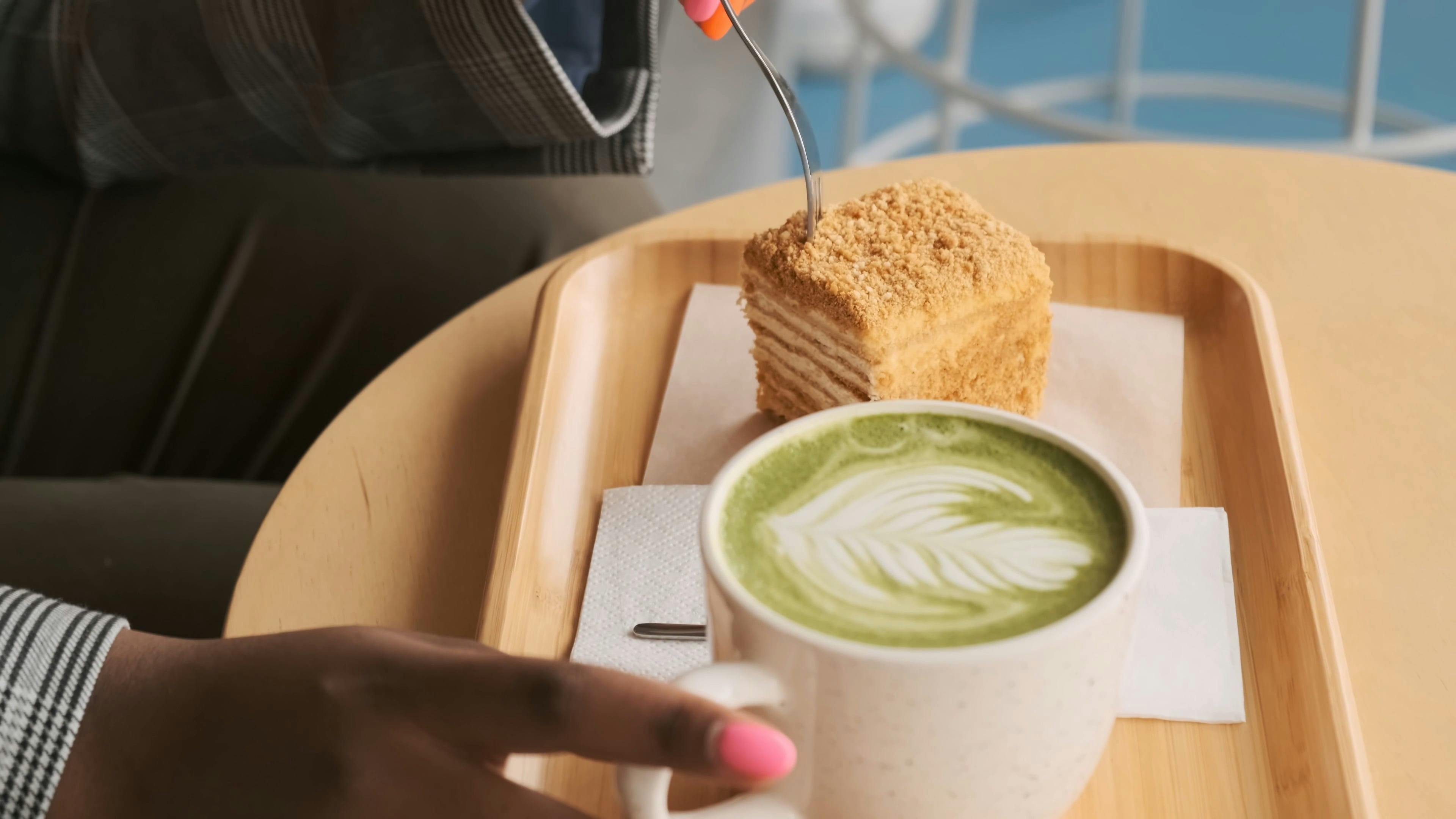 Primer Plano De Una Mujer Disfrutando De Comer Un Pastel Junto A Una Taza  De Café Con Leche En Una Bandeja De Madera En Cámara Lenta · Vídeo de stock  gratuito