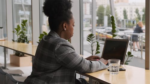 A Woman Working On A Laptop Over A Counter Type Table