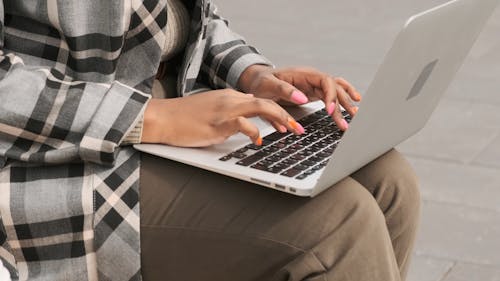 A Woman Seated In A Bench Outdoor Working On Her Laptop