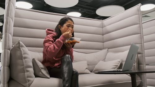 A Woman Working On Her Laptop While Eating 