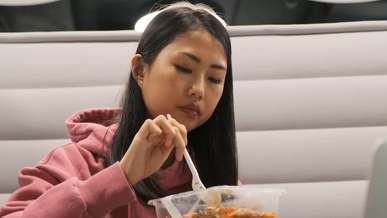 a woman eating her lunch while still in monitor of her laptop