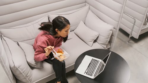 Een Vrouw Die Haar Voedsel Eet Terwijl Het Aan Haar Laptop Werkt