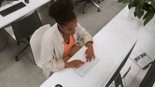現代のオフィススペースでデスクトップコンピュータで作業している女性の上面図