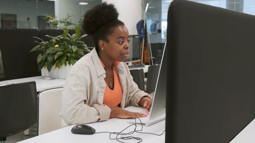 Сидящая женщина работает за компьютером в офисе