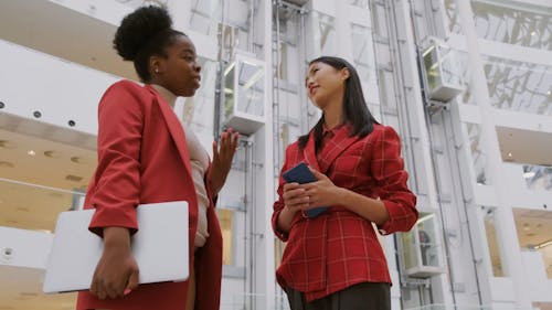 Dua Wanita Berdiri Berdiskusi Dengan Lift Bergerak Sebagai Latar Belakang