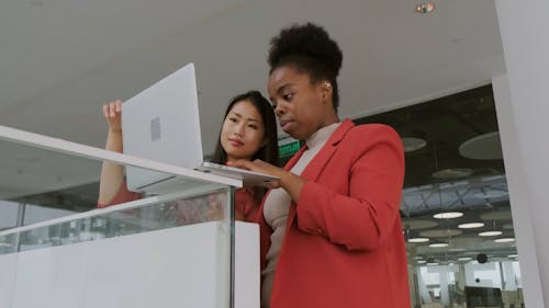 Een Vrouw Met Behulp Van Een Laptop Op Een Richel Met Een Andere Vrouw Die Het Voor Haar Houdt