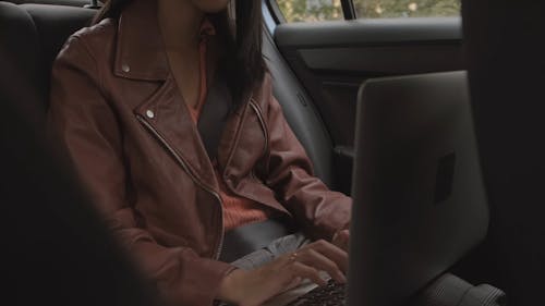 女人与她的车内的笔记本电脑一起工作