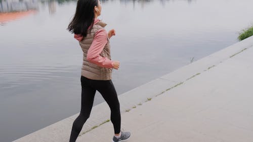 A Woman Does Her Jogging By The Side Of The River