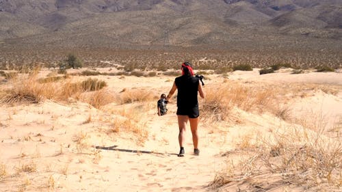 낮에는 언덕과 산 기슭의 모래 사막 부지에서 사진을 찍는 카메라를 가진 두 사람
