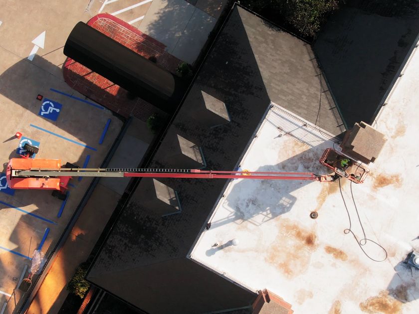 Crew using a lift to stage materials on a low-slope roof section