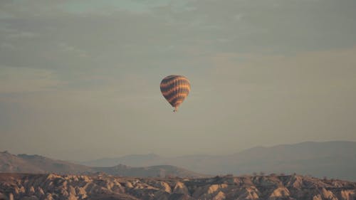 A Hot Air Balloon On Flight Above The Hills