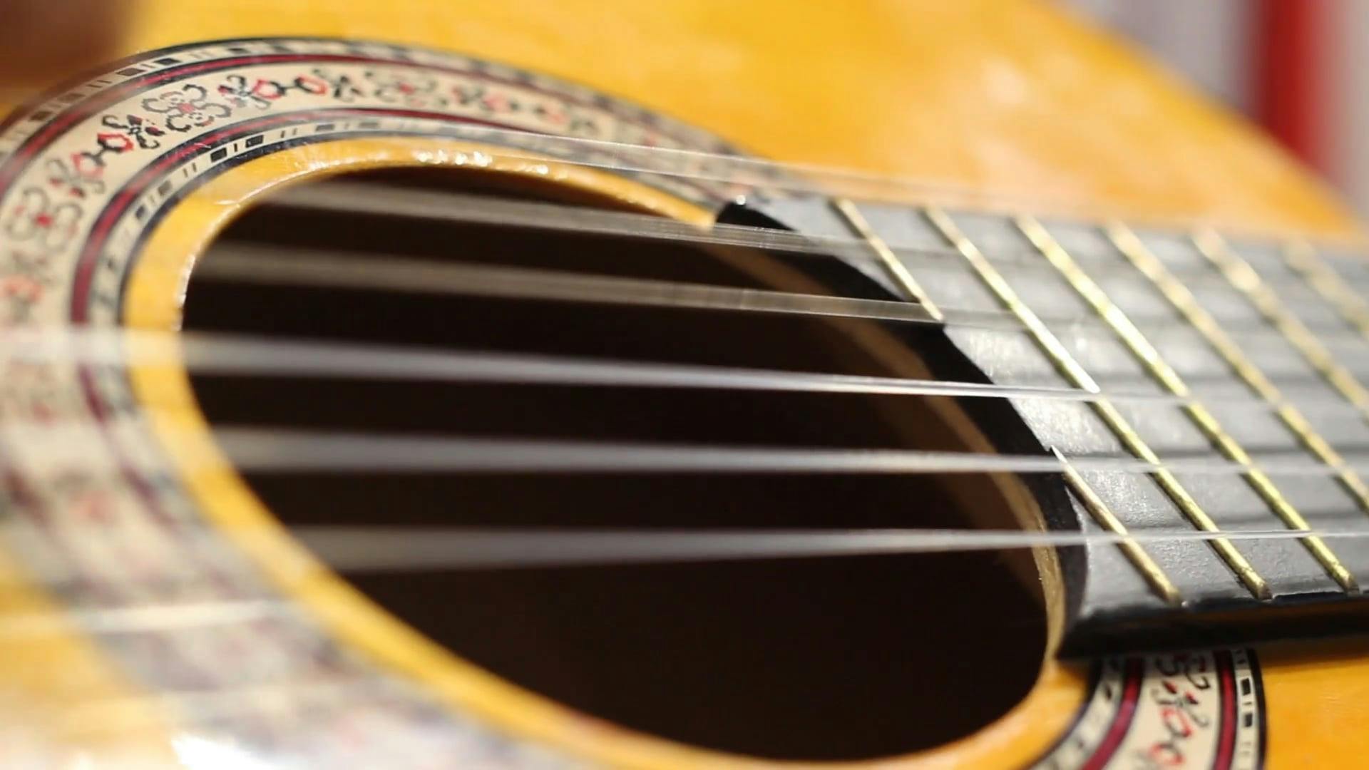 Closeup Of A Yellow Guitar With Its Strings Vibrating From The