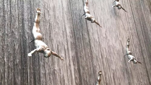 Sculptures Of Men Diving From A Waterfalls