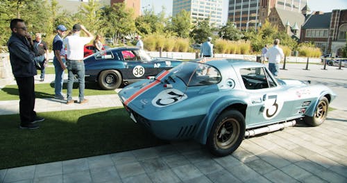 Slow Motion Footage Of People Looking Into Race Cars On Display Outdoor