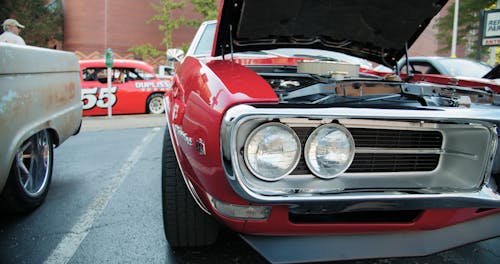 Close-up Of The Front End Of A Parked Classic Car With Its Engine Showing From The Open Hood