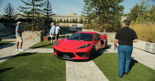 People Taking Pictures Of A Luxury Red Sports Cars Parked Outdoor