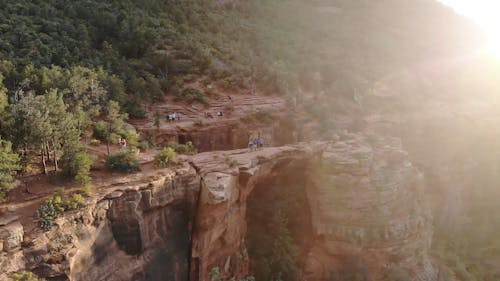 A Group Of People On Top Of A Natural Cliff Bridge Of A Rocky Mountain