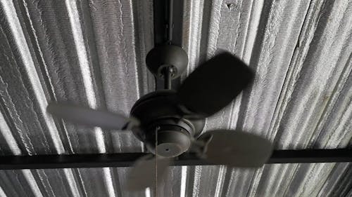 An Electric Fan Mounted To Flat Steel Bars Of A Ceiling
