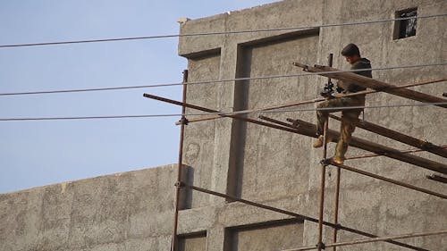 Low Angle Footage Of A Construction Worker Securing The Steel Scaffolding On The Building Exterior