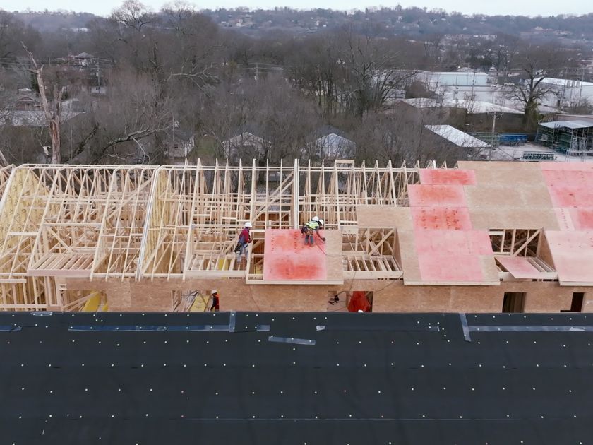Aerial view of the full crew sheathing a gable to ridge