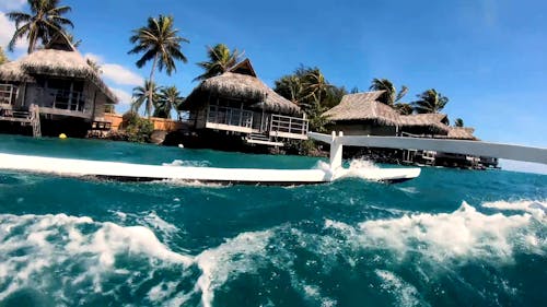 Low Angle Footage Of Cottages Along The Shoreline Of Of A Tropical Island Resort