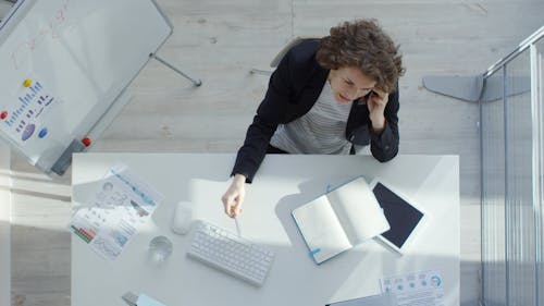 Femme Prenant Des Notes Tout En Parlant à Quelqu'un Au Téléphone