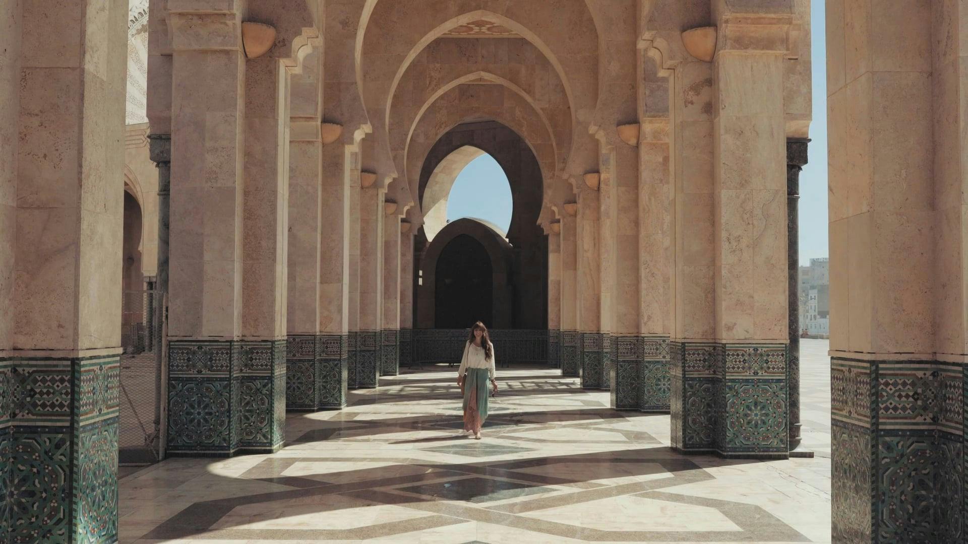 A Woman Walking On A Facade Of Concrete Pillars And Arches