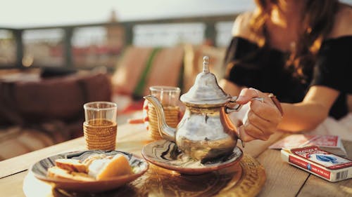 Een Vrouw Giet Thee In Een Glas Uit Een Theepot