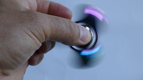 A Working Fidget Spinner In Between A Person's Fingers
