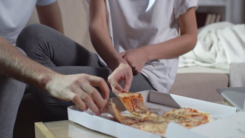 A Couple Eating Pizza On The Living Room