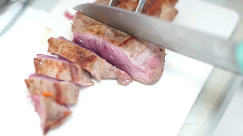 A Person Slicing A Piece Of Meat 