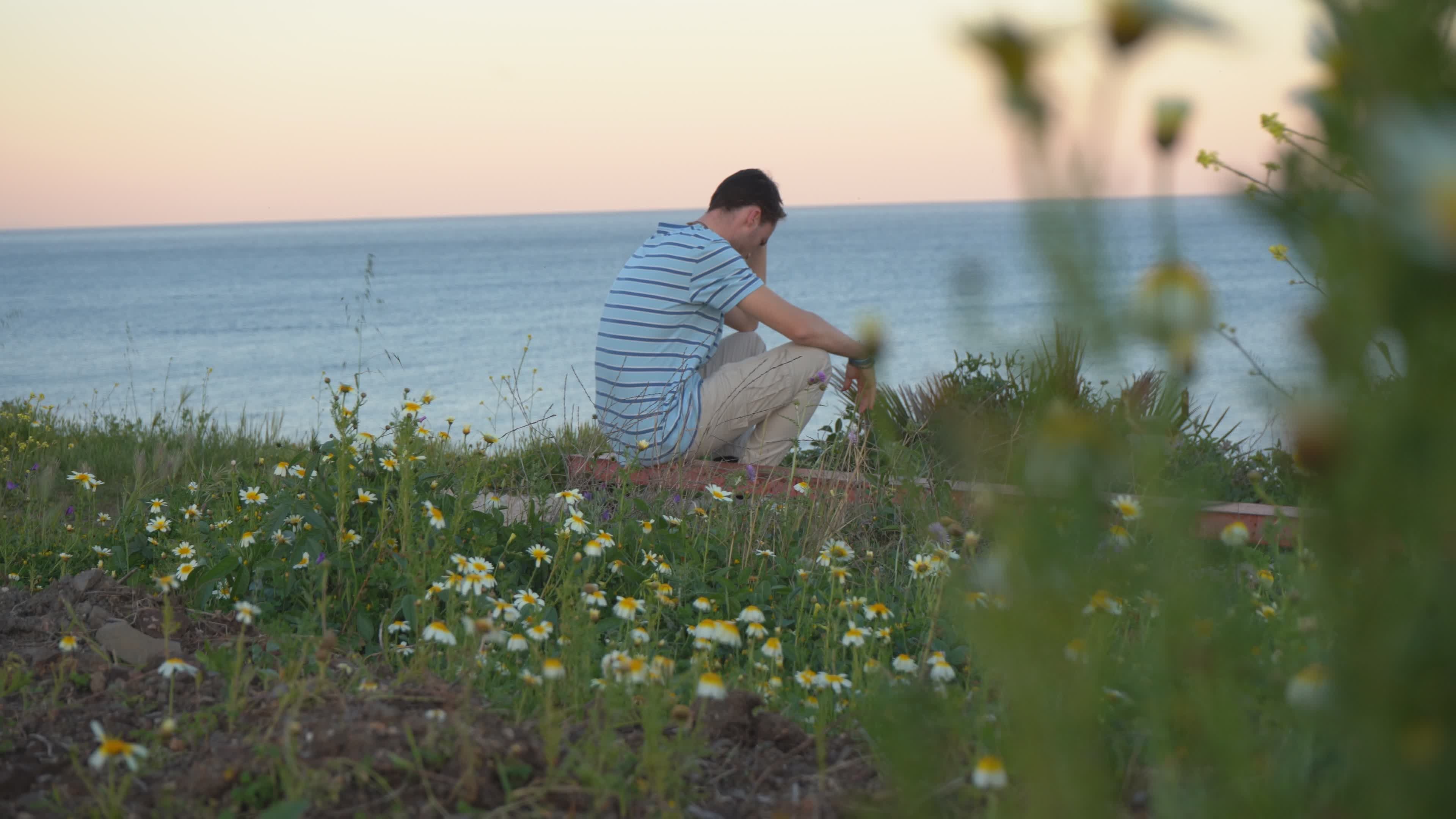 Contemplative Man Sitting by the Ocean at Sunset Free Stock Video ...