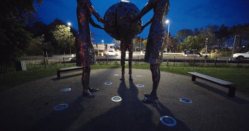 Three Women Sculptures In A Park Holding A Globe