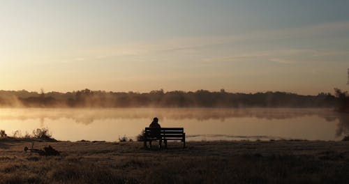 Seseorang Yang Duduk Sendiri Di Bangku Di Depan Danau