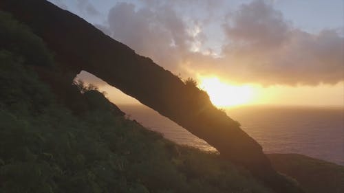 山の断崖から海の地平線に沈む夕日の眺め