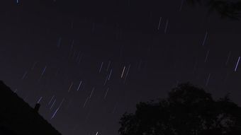 星轨延长，同时一颗人造卫星划过天际视频素材