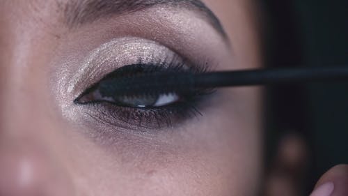 A Woman Applying Mascara To Thickens And Enhanced Her Eye Lashes