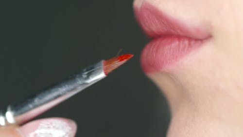 Eine Frau, Die Auf Rotem Lippenstift Auf Ihren Lippen Bürstet