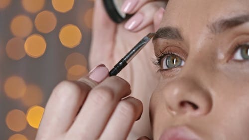 A Makeup Artist Applying Makeup On A Woman's Eyebrow 