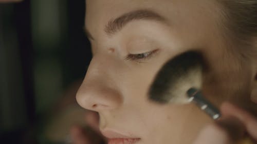 Applying A Dark Color Blush-on Makeup On A Woman Cheeks
