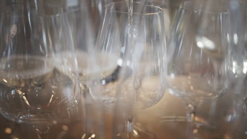 Pouring White Wine On Wine Glasses In Row