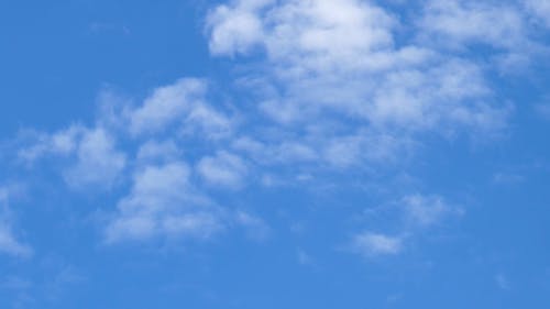 An Aircraft Flying Through The Clouds Under A Blue Sky