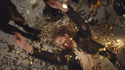 A Man Lying On A Floor Welcomes Confetti Dropping From Above