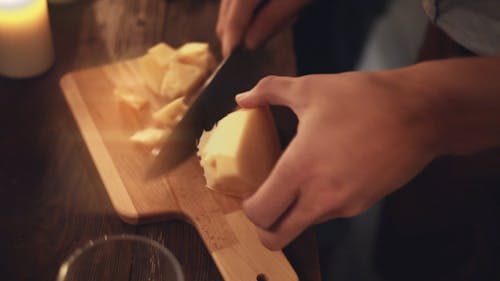A Person Cutting a Block Of Cheese Into Pieces