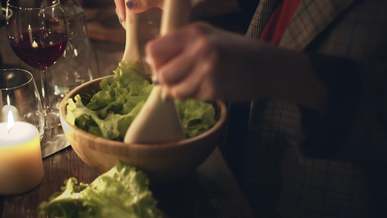 a person tossing a vegetable salad in a bowl