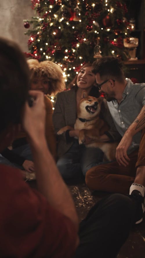 Toma De Fotografías De Un Grupo Con Un Perro Junto Al árbol De Navidad