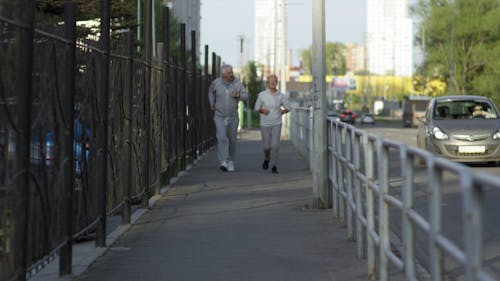 An Elderly Couple Jogging On The Sidewalk