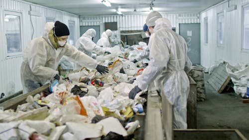 People Sorting Out Through A Pile Of Plastics