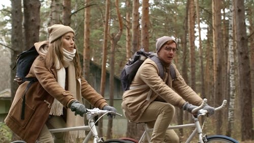 Two People Having A Conversation While Riding In Bicycles In The Woods