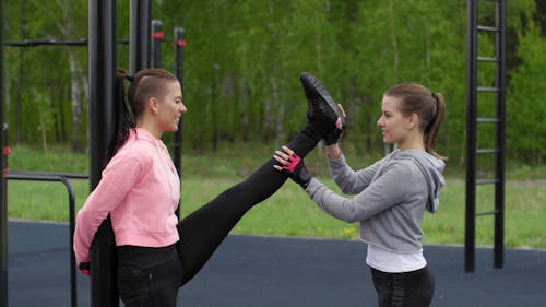 A Woman Assisting Another Woman Lift Her Leg For A Full Stretch